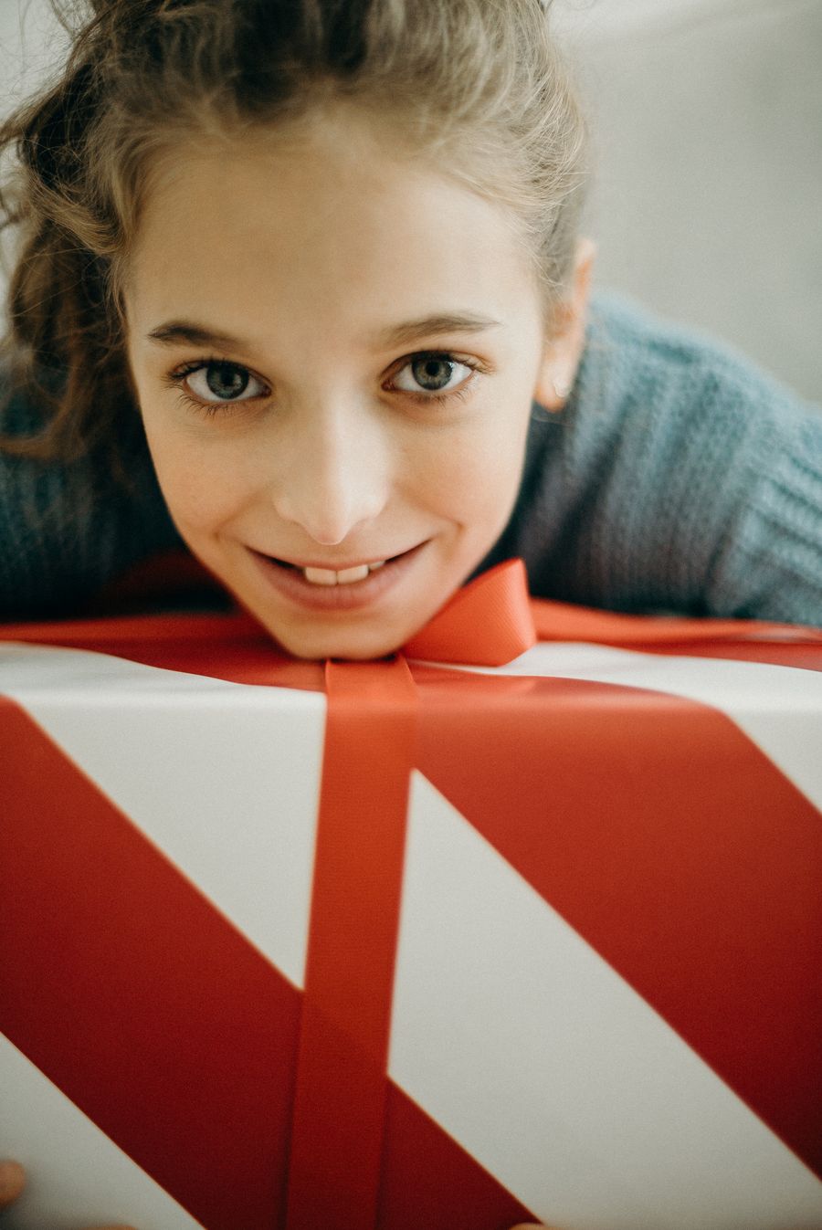 Smiling girl hugging a red and white wrapped Christmas gift